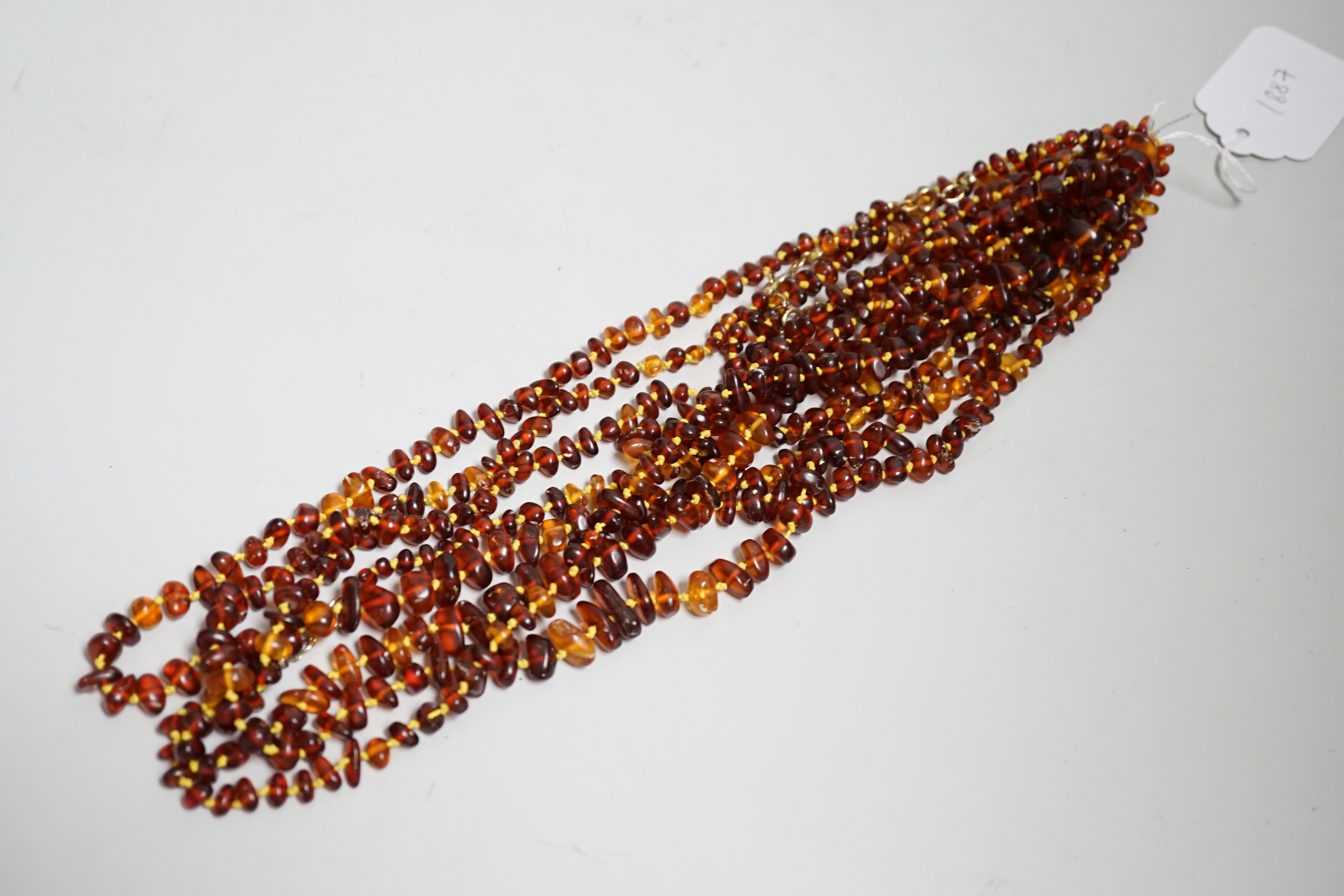 Five assorted single strand amber bead necklaces.